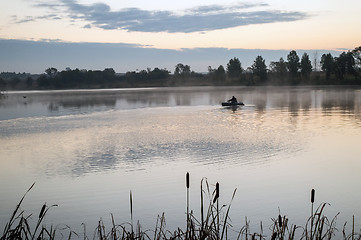 Image showing A fisherman in a boat sailing in the morning mist