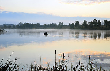 Image showing A fisherman in a boat sailing in the morning mist