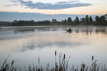 Image showing A fisherman in a boat sailing in the morning mist