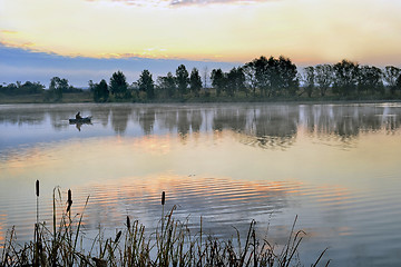 Image showing A fisherman in a boat sailing in the morning mist