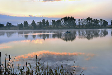 Image showing A fisherman in a boat sailing in the morning mist