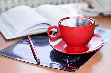 Image showing Red cup of coffee on the desk in the office