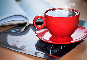 Image showing Red cup of coffee on the desk in the office