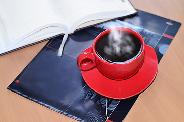 Image showing Red cup of coffee on the desk in the office