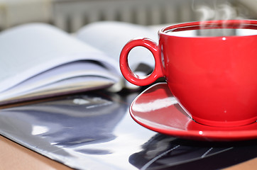 Image showing Red cup of coffee on the desk in the office