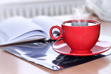 Image showing Red cup of coffee on the desk in the office