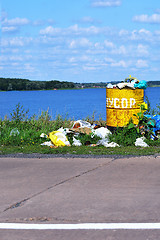Image showing Overflowing barrel with rubbish and waste disposal on the waterf