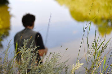 Image showing Blurred silhouette of fisherman on the river on a clear summer d