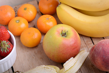 Image showing Bananas apple mandarin peach strawberry on wooden background as health food concept