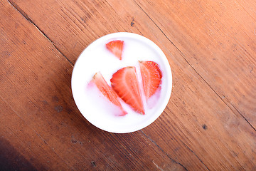 Image showing Slice of pie with strawberry on white plate, milk drink, wooden background. Top view