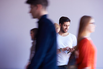 Image showing student working on tablet, people group passing by