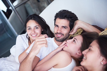 Image showing handsome man in bed with three beautiful woman