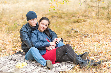 Image showing Young romantic couple sits on plaid. Autumn picnic