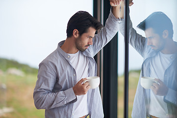 Image showing relaxed young man drink first morning coffee withh rain drops on