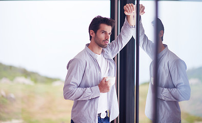 Image showing relaxed young man drink first morning coffee withh rain drops on