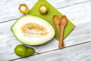 Image showing Cut melon honey and green pear on wood