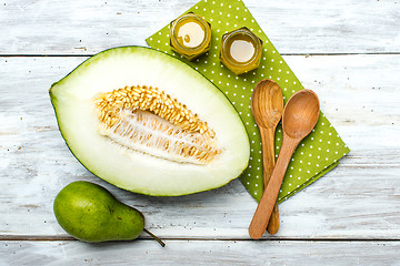 Image showing Ripe melon honey and pear on white wood