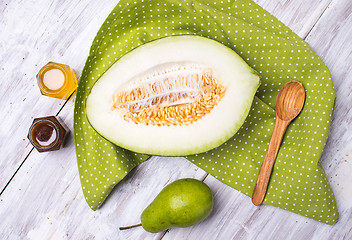 Image showing tasty melon with honey and pears on wood