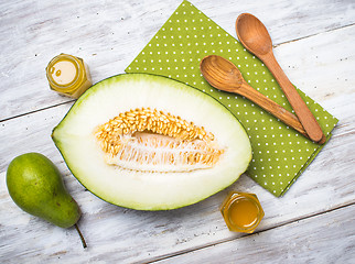 Image showing Ripe melon with honey and pear on white wood