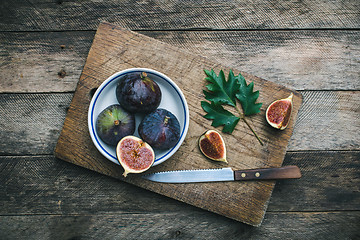Image showing Figs and knife on chopping board and wooden table
