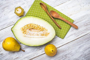 Image showing tasty melon with honey and yellow pears on white wood