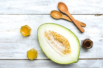 Image showing melon spoon and honey on white board