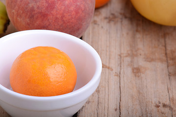 Image showing Mandarin Apples Bananas Peach on wooden plate