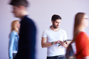 Image showing student working on tablet, people group passing by