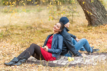 Image showing Young romantic couple sits on plaid. Autumn picnic