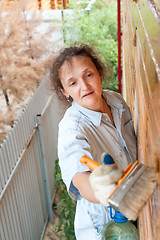 Image showing Pretty woman paints her wooden house