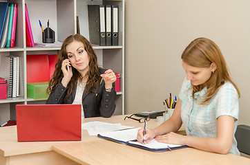 Image showing Discouraged chairwoman talking on a cell phone, an employee of the office wrote in a document