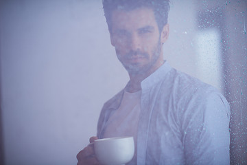 Image showing relaxed young man drink first morning coffee withh rain drops on