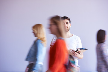 Image showing student working on tablet, people group passing by