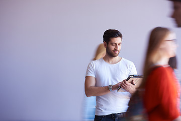 Image showing student working on tablet, people group passing by