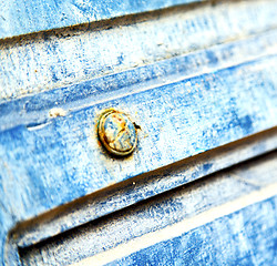 Image showing stripped paint in the blue wood door and rusty nail