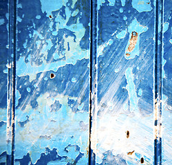 Image showing dirty stripped paint in the blue wood door and rusty nail