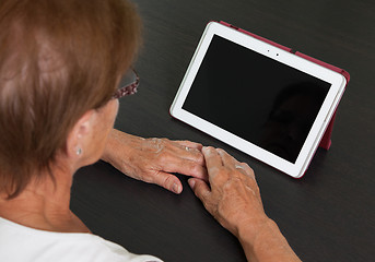 Image showing Senior lady relaxing and reading the screen of her tablet