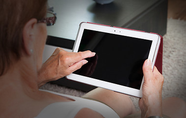 Image showing Senior lady relaxing and reading the screen of her tablet