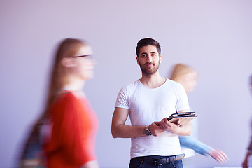 Image showing student working on tablet, people group passing by