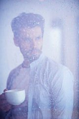 Image showing relaxed young man drink first morning coffee withh rain drops on