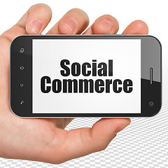 Image showing Marketing concept: Hand Holding Smartphone with Social Commerce on display