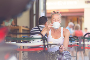 Image showing Woman drinking coffee outdoor on street.