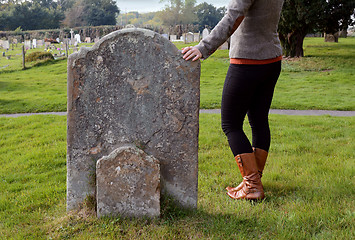 Image showing Woman rests her hand thoughtfully on a headstone