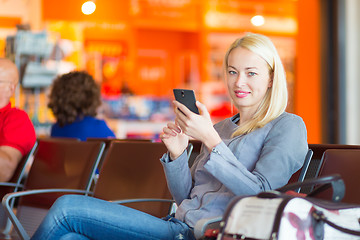 Image showing Female traveler using cell phone while waiting.