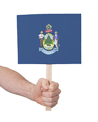 Image showing Hand holding small card - Flag of Maine