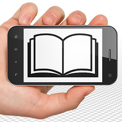 Image showing Science concept: Hand Holding Smartphone with Book on display