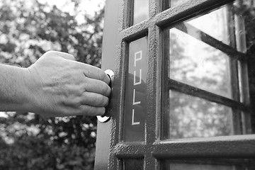 Image showing Man\'s hand pulls open door of phone box