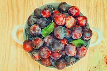 Image showing Large plum in a ceramic vase on the table.