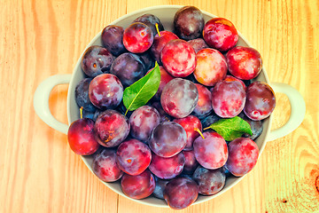 Image showing Large plum in a ceramic vase on the table.