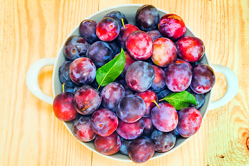 Image showing Large plum in a ceramic vase on the table.